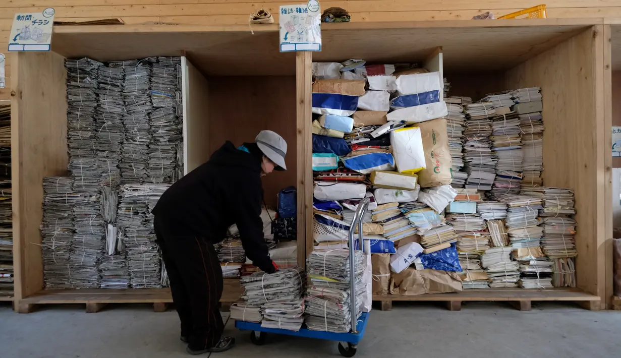 Pekerja menyortir koran dan majalah untuk didaur ulang di pusat limbah di Kamikatsu, Prefektur Tokushima, 14 Maret 2019. Kota di barat daya Jepang ini mengumumkan pada tahun 2003 bahwa pada tahun 2020 akan berhenti menghasilkan limbah sama sekali sebagai tujuan zero waste-nya. (Kazuhiro NOGI/AFP)