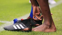 Yerry Mina melepaskan sepatu saat menginjak rumput Stadion Camp Nou (13/1/2018). Mina mengutip ayat Alkitab “Sentuhlah negeri yang ingin Anda taklukkan dengan telapak kaki Anda.” Dan di sini saya ingin membuat sejarah dengan semua orang. (AFP/Pau Barrena)
