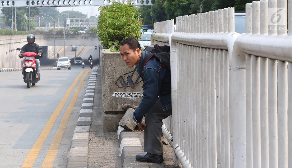 Seorang pria menerobos pagar pembatas jalan di kawasan Pasar Minggu, Jakarta, Kamis (5/4). Kondisi Jembatan Penyeberangan Orang (JPO) yang tak kunjung diperbaiki membuat warga nekat menyeberang lewat celah pagar pembatas. (Liputan6.com/Immanuel Antonius)