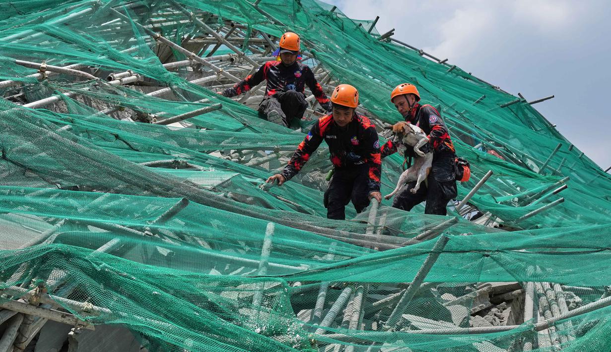 Para penyelamat membawa seekor anjing saat mereka menuruni penyangga yang roboh dari sebuah bangunan yang runtuh di kota Angeles, provinsi Pampanga, utara Manila, Filipina, Senin 25 Mei 2026. (AP Photo/Aaron Favila)