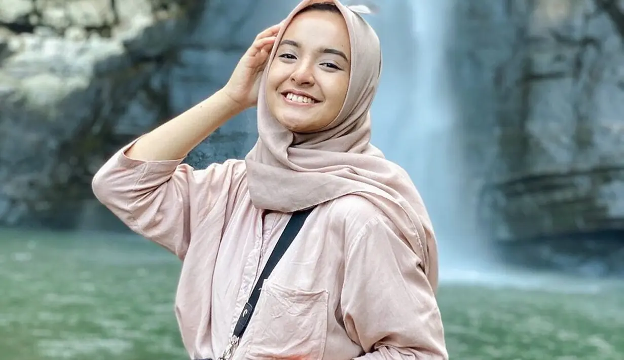 Nabila Ishma berusaha untuk terus tersenyum lebar seperti janjinya ke Eril. Nabila memiliki senyum yang sangat manis. Terlebih saat tersenyum ketika ia jalan-jalan destinasi wisata air terjun. Senyum manisnya ini banjir like dari netizen. (Liputan6.com/IG/@nabilaishma)