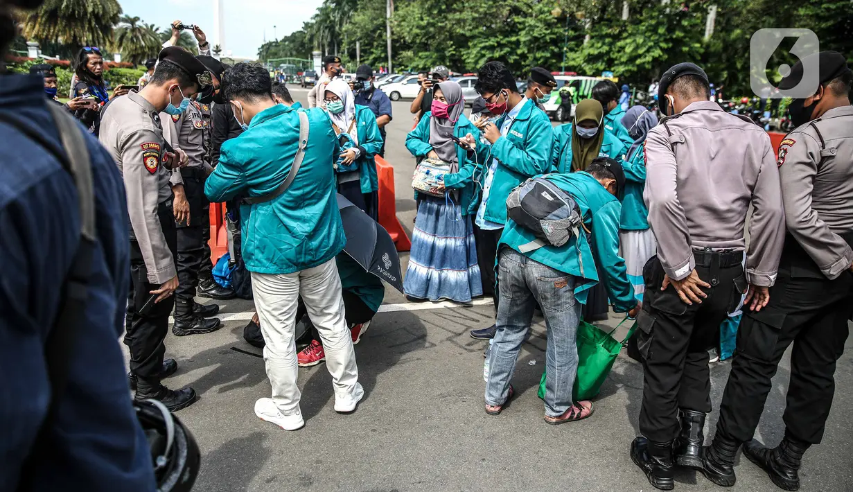 Polisi memeriksa barang bawaan mahasiswa yang akan berunjuk rasa di Patung Kuda, Jakarta, Selasa (20/10/2020). Pemeriksaan tersebut dilakukan untuk memastikan unjuk rasa berjalan aman dan damai. (Liputan6.com/Faizal Fanani)