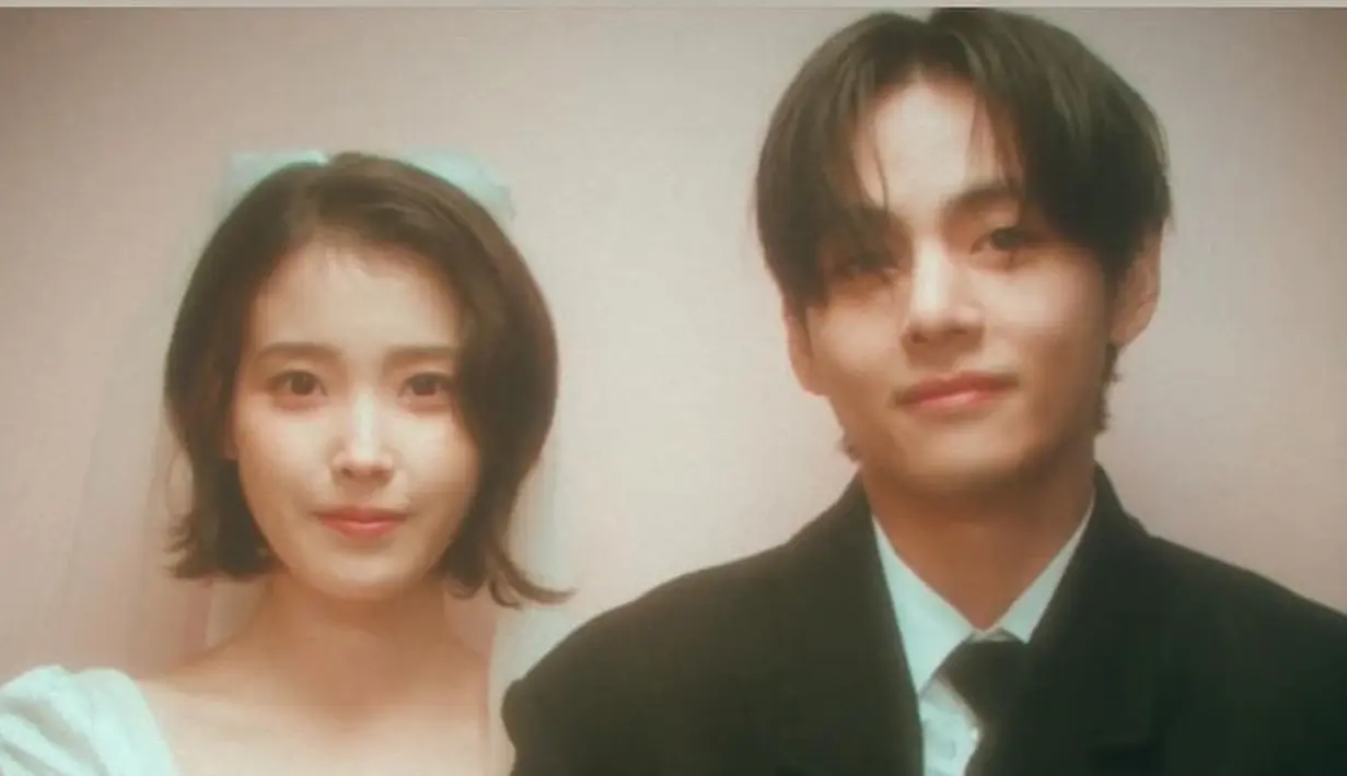 IU tampil mengenakan gaun putih lengan panjang dengan kerah square. Sementara V tampil mengenakan setelan jas hitam lengkap dengan dasinya. [YouTube/ IU Official]