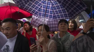 Kerabat dan guru siswa yang mengikuti ujian masuk perguruan tinggi nasional tahunan yang juga dikenal sebagai "Gaokao" menunggu sesi pagi selesai saat hujan turun di Beijing, China, Jumat (7/6/2024). (AP Photo/Ng Han Guan)