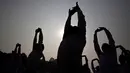 Siluet anggota nasionalis Hindu Rashtriya Swayamsevak Sangh (RSS) saat mengikuti yoga massal di Gauhati, India (21/1). Menurut seorang pejabat RSS, yoga massal ini diikuti lebih dari tiga puluh ribu sukarelawan. (AP Photo / Anupam Nath)