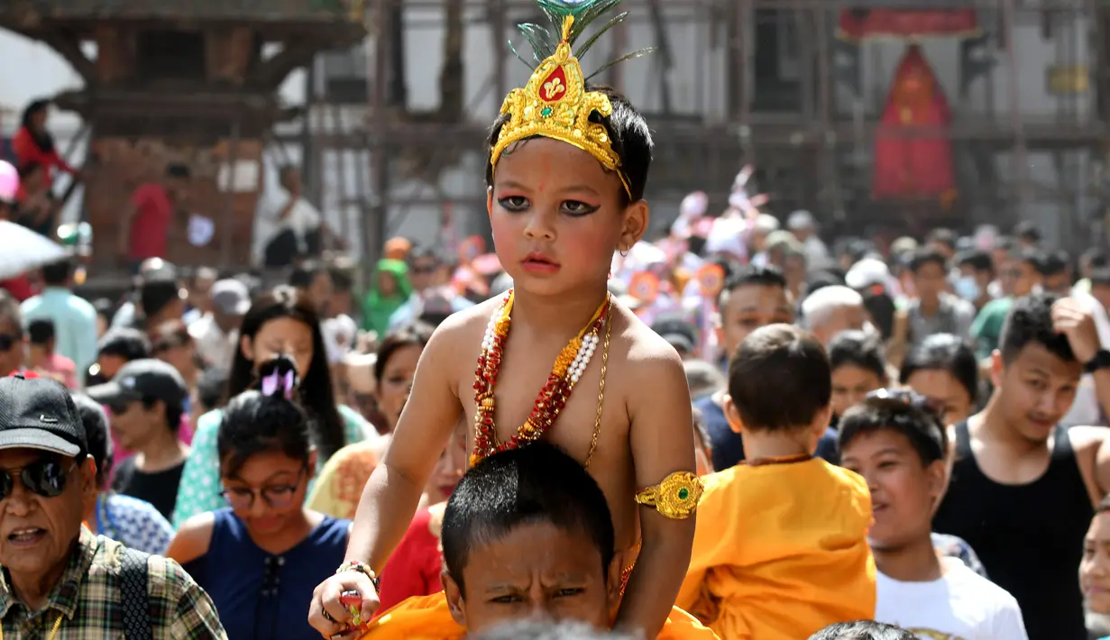Seorang anak Nepal mengenakan kostum seperti dewa Krishna mengikuti Gai Jatra cow festival di Kathmandu, Nepal (8/8). Festival Gai jatra ini juga disebut festival sapi dan cukup populer di Nepal. (AFP Photo/Prakash Mathema)