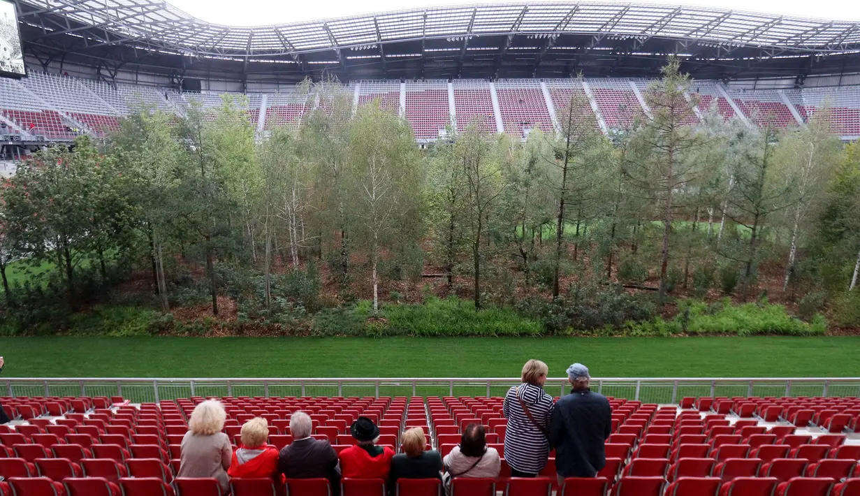 Pengunjung melihat instalasi ekosistem hutan di Stadion Woerthersee, Austria, Minggu (8/9/2019). Lebih dari 300 pohon berbagai jenis , mulai dari pohon aspen, ek, betula, hingga larix ditancapkan dalam karya seni yang berjudul "The Unending Attraction of Nature". (AP/Ronald Zak)