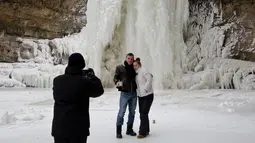 Pengunjung berpose di depan air terjun Mirusha yang membeku di Lapceve, Kosovo (9/1). Ekstremnya cuaca yang melanda sebagian eropa menyebabkan puluhan orang tewas dan keberangkatan pesawat di tunda. (AP Photo/Visar Kryeziu)