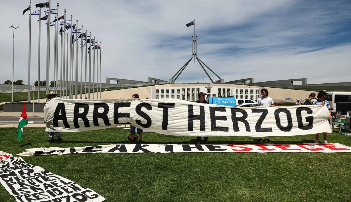 Selama di Australia, Presiden Israel, Isaac Herzog, dijadwalkan akan menghadiri upacara penghormatan bagi korban penembakan di Bondi Beach yang terjadi pada Desember 2025, yang menargetkan perayaan Hanukkah. Tampak dalam foto, para pengunjuk rasa berkumpul di depan gedung Parlemen menjelang pertemuan antara Perdana Menteri Australia Anthony Albanese dan Presiden Israel Isaac Herzog di Canberra pada Rabu 11 Februari 2026. (David GRAY/AFP)