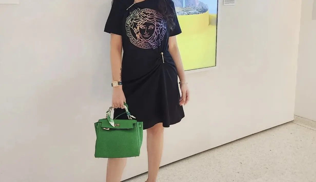 Poppy tampil dengan dress hitam dari Versace, ia pun menenteng tas Dior warna hijau.[Instagram/@poppycapella_]