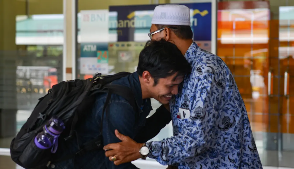 Seorang mahasiswa (kiri) yang dipulangkan dari karantina virus corona atau COVID-19 di Natuna menyalami keluarganya saat tiba di Bandara Internasional Sultan Iskandar Muda, Blang Bintang, Aceh, Senin (17/2/2020). Ada 13 mahasiswa Aceh yang mengikuti karantina di Natuna. (CHAIDEER MAHYUDDIN/AFP)