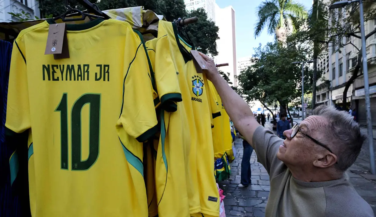 Seorang pria melihat kaus tim sepak bola nasional Brasil yang dipajang di pasar Saara, Rio de Janeiro, Brasil, pada Selasa 9 Juni 2026, menjelang turnamen Piala Dunia FIFA 2026. (Nelson ALMEIDA/AFP)