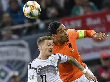 Bek Belanda, Virgil Van Dijk berebut bola udara dengan gelandang Jerman, Marco Reus selama pertandingan grup C  kualifikasi Euro 2020 di Hamburg, Jerman (6/9/2019). Belanda menang telak 4-2 atas Jerman. (AP Photo/Martin Meissner)