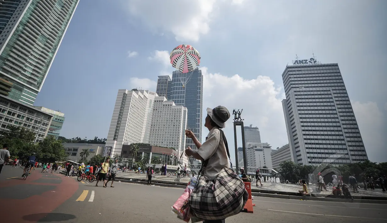 Pedagang parasut mainan saat menerbangkan barang dagangannya di kawasan Bundaran HI, Jakarta, Minggu (22/3/2015).  Seiring dengan perkembangan zaman dan modernisasi, permainan tradisional kini mulai tergantikan. (Liputan6.com/Faizal Fanani)