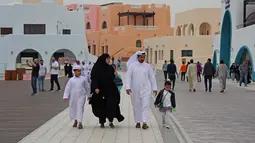 Keluarga berjalan-jalan selama ajang Piala Dunia 2022 Qatar di Distrik Mina Doha pada 10 Desember 2022. Karena strukturnya yang semarak, distrik ini dapat dilihat dari kejauhan. Baik penduduk maupun pengunjung mengatakan hal pertama yang akan Anda perhatikan adalah warna bangunan yang mencolok. (AFP/Christina Assi)