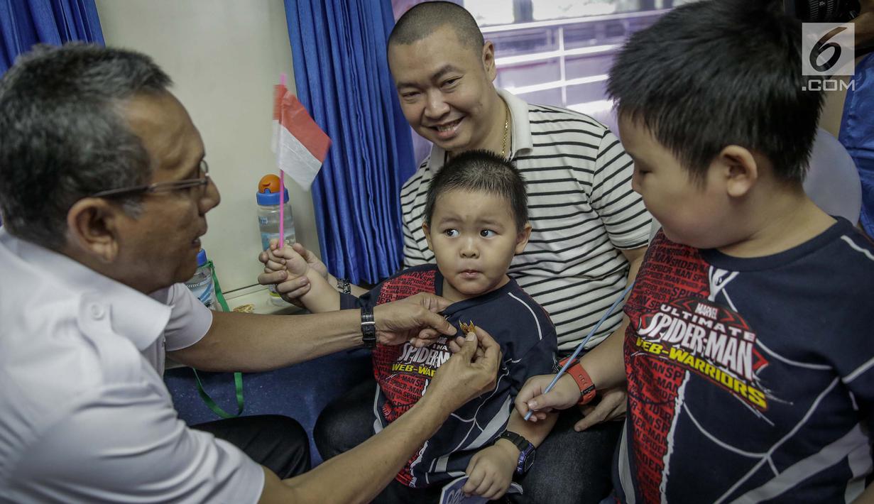 Petugas PT KAI Daop 1 memberikan pin garuda kepada penumpang di Stasiun Gambir, Jakarta, Kamis (1/6). Dalam rangka memperingati HUT Pancasila PT KAI Daop 1 memberikan pin dan bendera merah putih kepada penumpang kereta api. (Liputan6.com/Faizal Fanani)