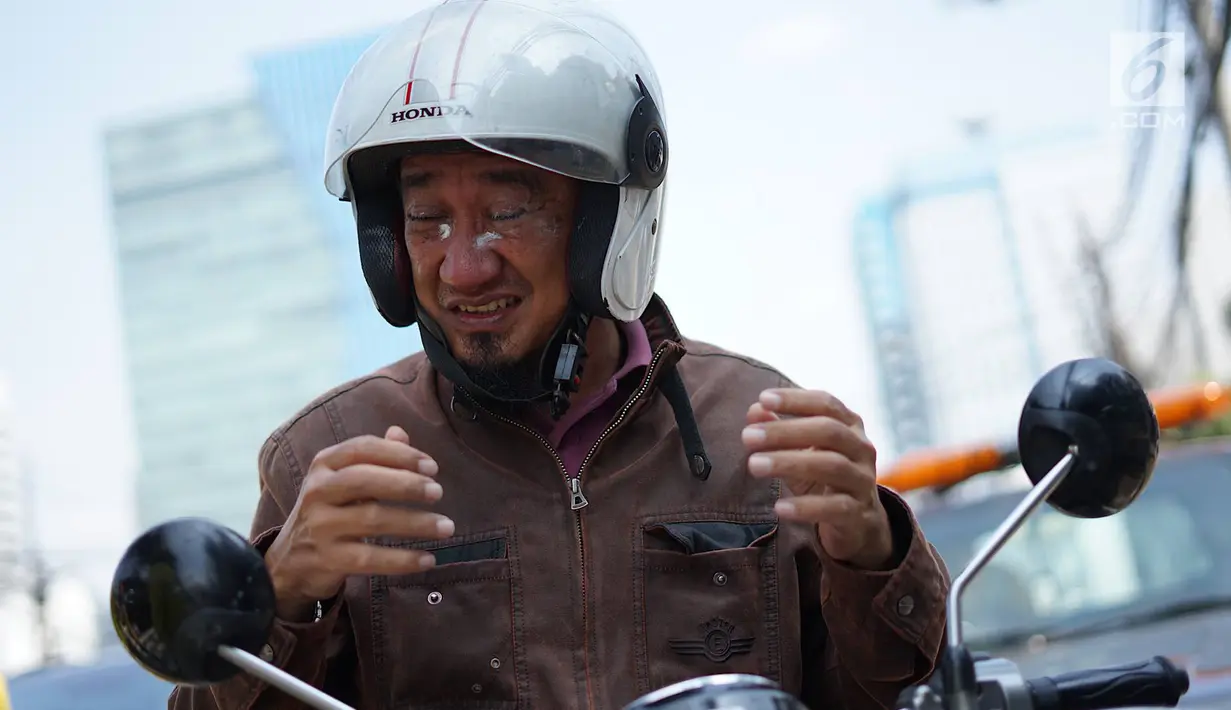 Pengendara motor mengoleskan pasta gigi ke wajahnya saat melintasi Jalan KS Tubun, Petamburan, Kamis (23/5/2019). Petugas Suku Dinas Bina Marga Jakarta Barat membagikan pasta gigi untuk mengurangi efek gas air mata yang digunakan untuk membubarkan massa aksi 22 Mei. (Liputan6.com/Immanuel Antonius)