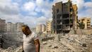 Seorang pria berjalan melewati sebuah lubang di mana sebuah bangunan yang runtuh berdiri setelah serangan udara Israel semalam di lingkungan Kafaat di pinggiran selatan Beirut, pada 7 Oktober 2024. (Foto oleh AFP)