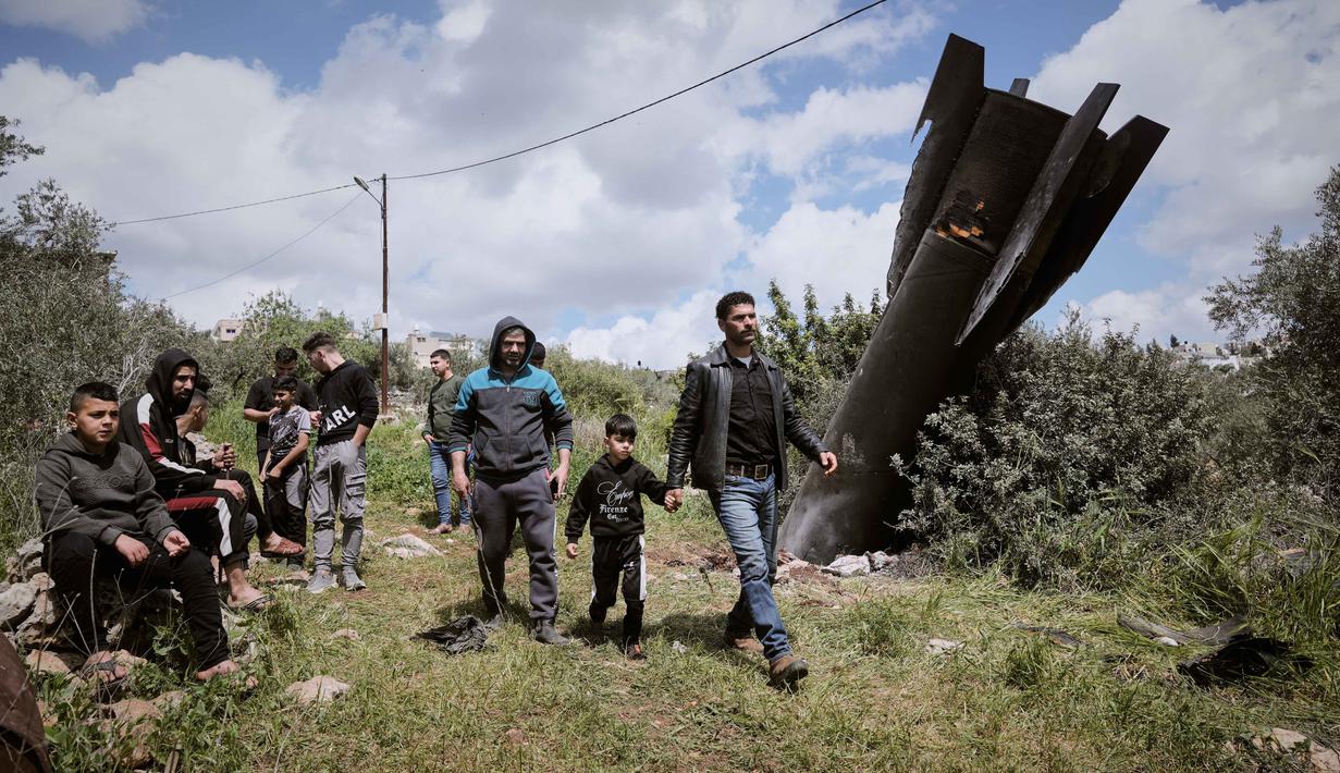 Puing rudal Iran ditemukan di desa Kifl Haris, dekat Nablus, Tepi Barat pada Selasa 24 Maret 2026. Tampak dalam foto, warga Palestina mengamati puing-puing rudal Iran yang jatuh di desa Kifl Haris, Tepi Barat, Selasa, 24 Maret 2026. (AP Photo/Majdi Mohammed)