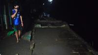 Warga di Kampung Putih, Rampal Celaket, Kota Malang, berdiri di atas puing rumah tetangganya yang rata karena hanyut ke sungai dapak banjir bandang di Batu dan Malang pada Kamis, 4 November 2021 (Liputan6.com/Zainul Arifin)