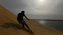Seorang pria berseluncur menggunakan papan sandboards di gurun pasir Wadi el-Rayan Fayoum, Mesir (18/11). Sandboarding ini hampir sama dengan snowboarding, yang membedakan adalah medannya yakni di pasir. (Reuters/Mohamed Abd El Ghany)