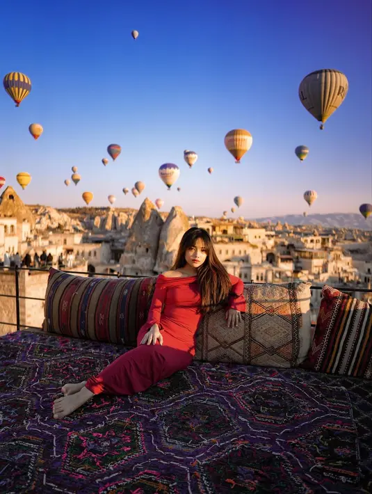 Cara tampil stand out dengan latar pemandangan balon udara warna-warni Cappadocia, dress warna yang kontras seperti merah merona seperti yang dikenakan Fuji bisa jadi pilihan. [@fuji_an]