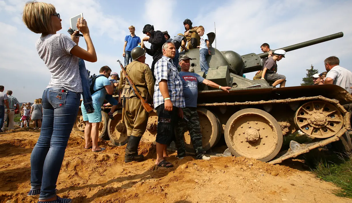 Sejumlah pengunjung berfoto diatas tank yang digunakan sebagai properti setelah pertunjukan rekonstruksi pertempuran Perang Dunia II, di Memorial "Stalin Line", dekat Desa Goroshki, Belarusia, (10/9). (Reuters/Vasily Fedosenko)