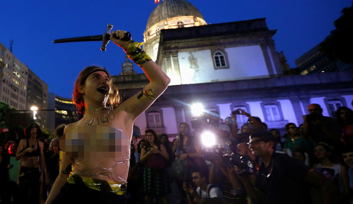 Seorang wanita dari sebuah kelompok seni bertelanjang dada saat berunjuk rasa memprotes maraknya pemerkosaan dan kekerasan seksual di pusat kota Rio de Janeiro, Brasil, Rabu (1/6). (REUTERS/Ricardo Moraes)