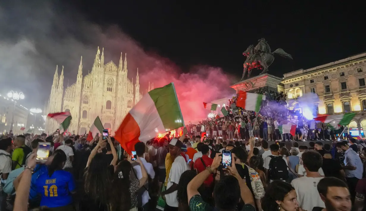Suporter merayakan kemenangan Italia atas Inggris pada pertandingan final Euro 2020 di depan Katedral Duomo, Milan, Italia, Senin (12/7/2021). Italia menjuarai Euro 2020 usai mengalahkan Inggris lewat drama adu penalti pada pertandingan final. (AP Photo/Luca Bruno)