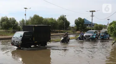 Sejumlah kendaraan melintasi banjir rob di kawasan Pelabuhan Perikanan Samudera Nizam Zachman, Muara Baru, Jakarta, Sabtu (6/11/2021). Banjir rob tersebut disebabkan karena naiknya permukaan air laut. (Liputan6.com/Herman Zakharia)