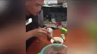 Seorang pria tampak mencelupkan bayi tikus yang masih hidup ke dalam kecap asin sebelum memakannya