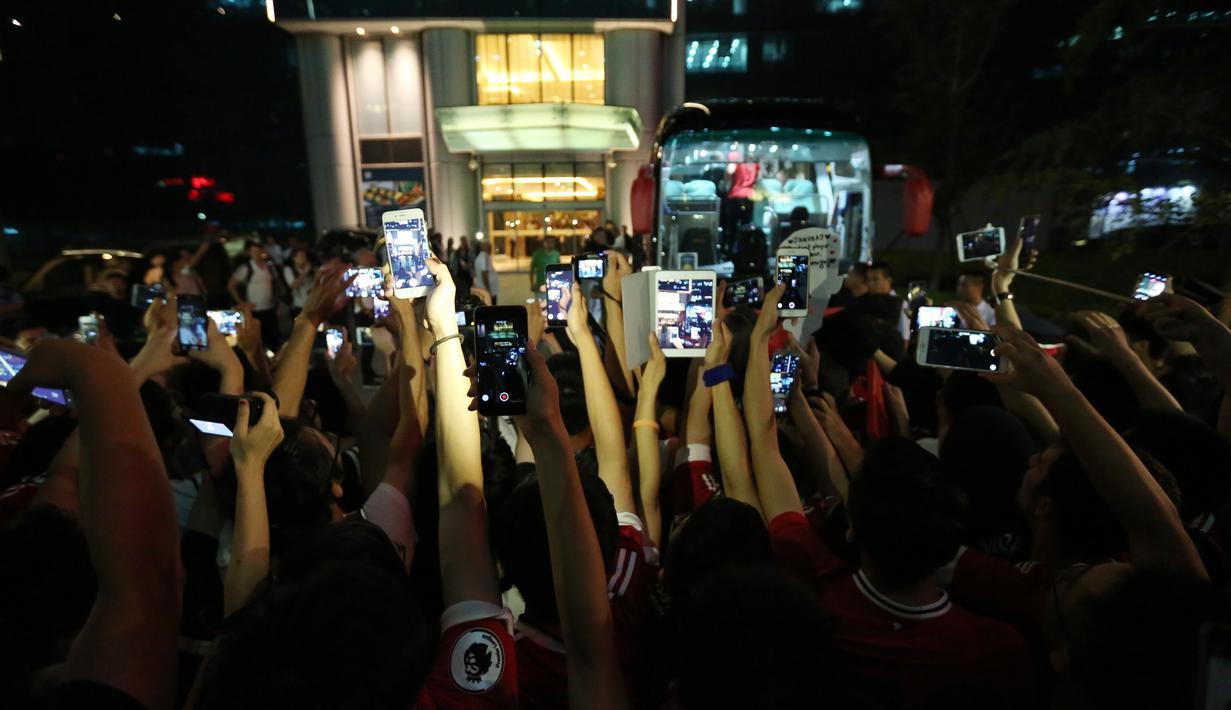  Suporter Manchester United mengambil foto pemain MU saat memasuki bus yang akan membawa ke bandar udara setelah pertandingan melawan Manchester City dibatalkan di Beijing, China. (25/7/2016). (AFP)