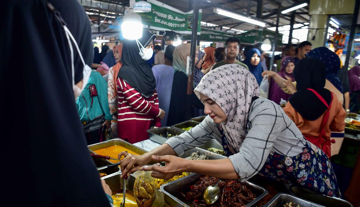 Diketahui, Provinsi Narathiwat, memiliki populasi Muslim mayoritas di Thailand. Tampak dalam foto, seorang penjual makanan kaki lima mengemas makanan untuk berbuka puasa di sebuah kios pada hari pertama bulan suci Ramadan 1447 Hijriah di sebuah pasar di provinsi Narathiwat, Thailand selatan, pada Kamis 19 Februari 2026. (Madaree TOHLALA/AFP)