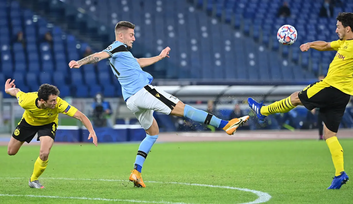 Gelandang Lazio, Sergej Milinkovic-Savic (tengah) berebut bola dengan pemain Borussia Dortmund, Marco Reus (kiri) dan Mats Hummels pada pertandingan perdana Grup F Liga Champions 2020 di Stadion Olimpico, Rabu (21/10/2020) dini hari WIB. Lazio menang 3-1 atas Borussia Dortmund. (Alberto PIZZOLI/AFP)