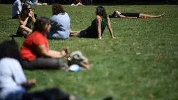 Seorang wanita tidur di bawah sinar matahari di Victoria Tower Gardens dekat Gedung Parlemen di London (23/7/2019). Suhu melonjak di atas 30C (86F) di Inggris pada 23 Juli dengan para peramal cuaca memperkirakan suhu setinggi 37C (96.8F) sebelum akhir pekan. (AFP Photo/Ben Stansall)