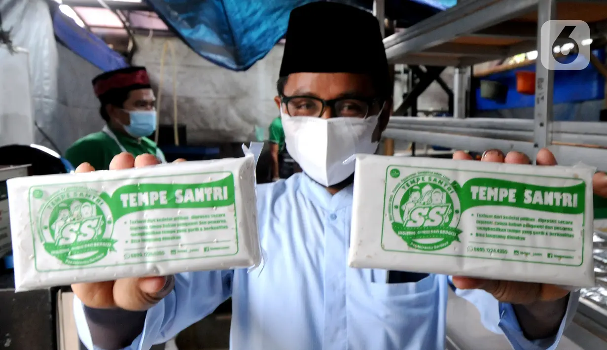 Soerang santri memperlihatkan tempe yang telah selesai dibuat di Pondok Pesantren Sirajussa'adah, Depok, Jawa Barat, Selasa (23/3/3021). Tempe Santri dijual dengan harga Rp 6.000 per bungkus. (merdeka.com/Arie Basuki)