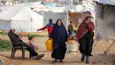 Kondisi ini memaksa jutaan warga Palestina di Gaza mengantre berjam-jam setiap kali truk bantuan air bersih datang, dengan jatah yang terkadang hanya tersedia seminggu sekali. Tampak dalam foto, para wanita berjalan membawa ember air dan jerigen setelah mengisi air dari tangki portabel di kamp pengungsi Palestina Maghazi, Jalur Gaza tengah pada Rabu 11 Februari 2026. (Eyad BABA/AFP)