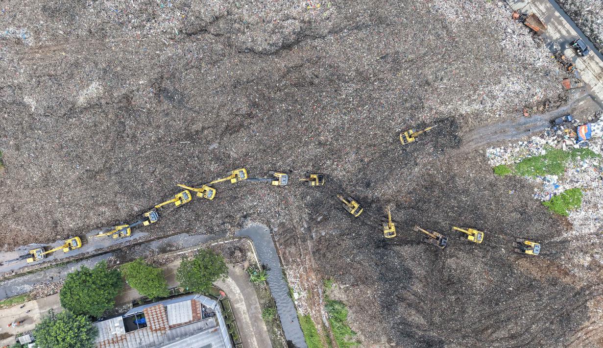 Longsoran sampah juga menimbun sejumlah truk sampah dan bangunan warung yang beroperasi di lokasi tersebut. Tampak foto udara menunjukkan tim penyelamat menggunakan alat berat untuk mencari korban longsor di Tempat Pembuangan Sampah Terpadu (TPST) Bantargebang, Bekasi, Jawa Barat, pada 9 Maret 2026. (BAY ISMOYO/AFP)
