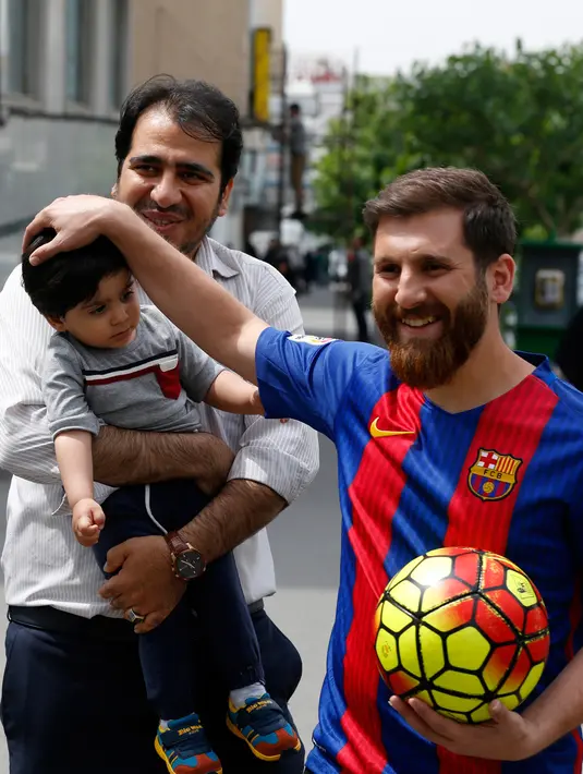 Pemuda Iran, Reza Parastesh yang berwajah mirip bintang Barcelona, Lionel Messi menyapa pejalan kaki di sebuah jalan di Teheran, Senin (8/5). Selain laris diwawancarai media, Parastesh juga kini telah meneken kontrak sebagai foto model. (ATTA KENARE/AFP)