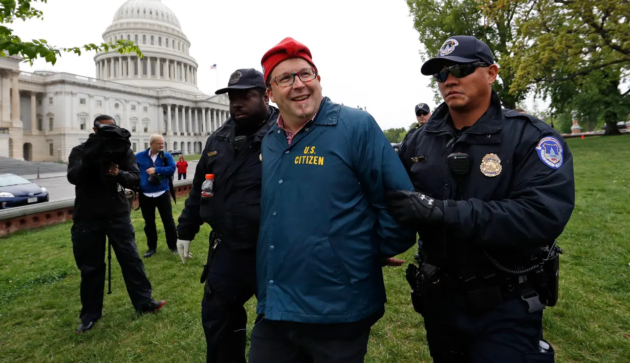 Petugas polisi mengamankan demonstran bernama Adam Eidinger saat menggelar aksinya di dekat gedung Capitol di Washington (24/4). (AP Photo/Alex Brandon)