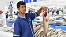 Seorang pedagang menunjukkan ikan yang dijual di pasar ikan Dubai, Uni Emirat Arab, Kamis (29/3). (GIUSEPPE CACACE/AFP)