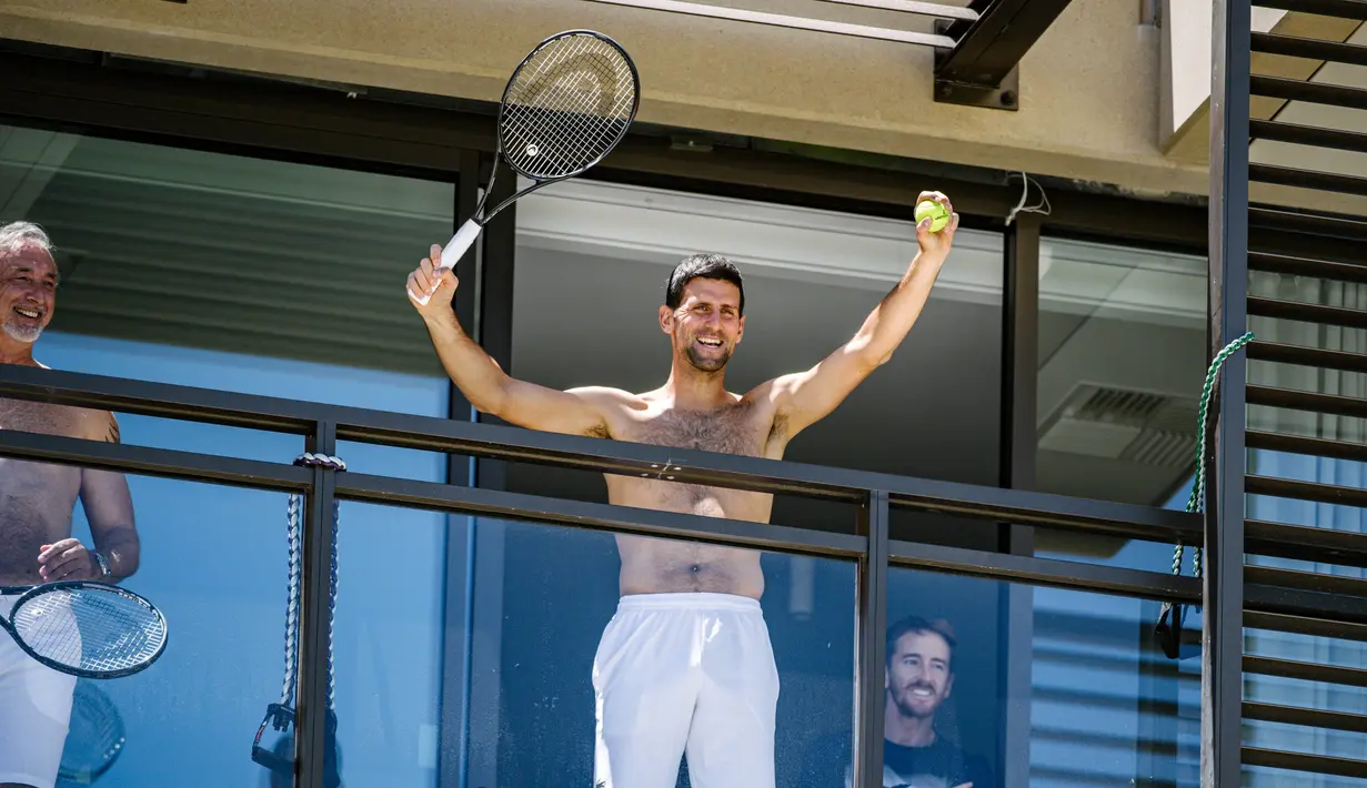 Petenis pria peringkat satu dunia, Novak Djokovic menyapa penggemarnya disela-sela menjalani latihan dari balkon hotel, Adelaide, Australia, Rabu (20/1/2021). (Foto: AFP/Morgan Sette)