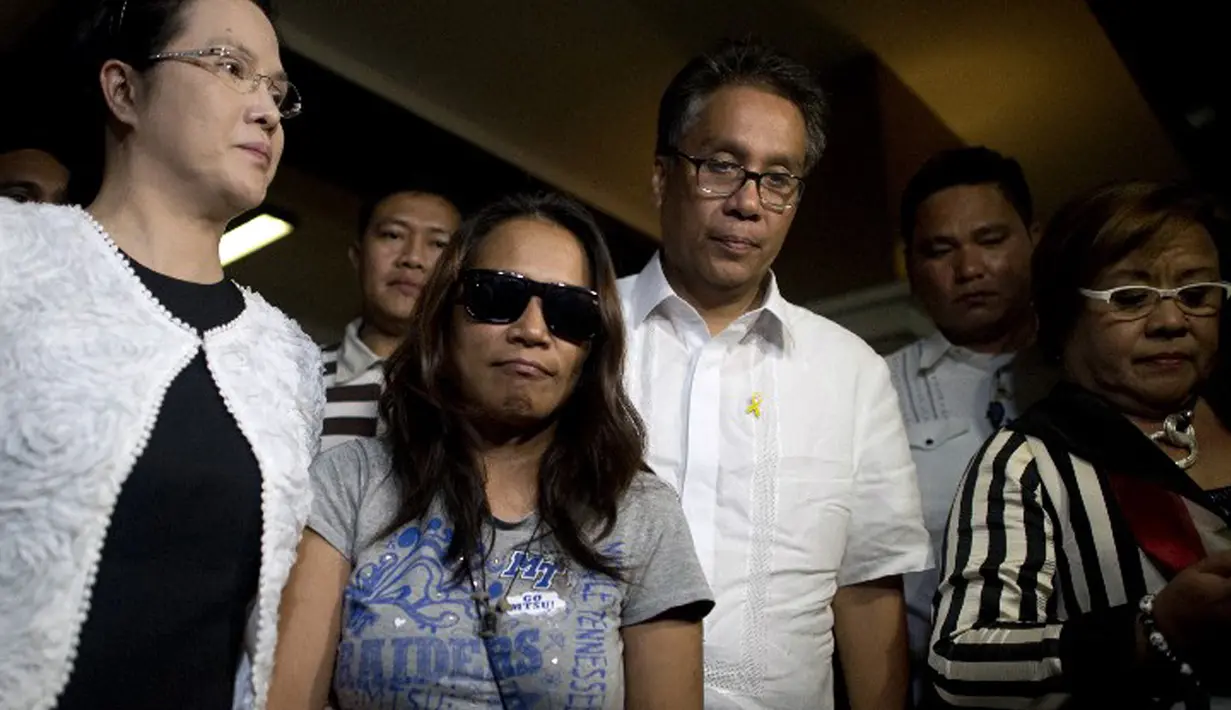 Petugas mengawal Maria Kristina Sergio (berkacamata hitam), perempuan yang diduga perekrut terpidana mati kasus narkoba Mary Jane, saat konferensi pers di markas polisi Camp Crame, Kota Quezon, Filipina, Rabu (29/4/2015). (AFP PHOTO/NOEL CELIS)