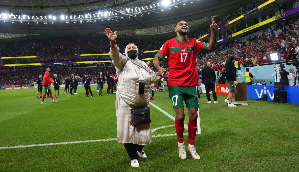 Gelandang Maroko #17 Sofiane Boufal merayakan bersama ibunya setelah lolos ke semifinal dengan mengalahkan Portugal pada babak 8 besar Piala Dunia 2022 di Stadion Al-Thumama di Doha, Sabtu (10/12/2022). Momen itu jadi salah satu yang membuat haru di samping rekor Maroko di Piala Dunia. (AP Photo/Petr David Josek)
