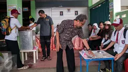 Warga menggunakan hak pilihnya pada Pilkada DKI 2017 di TPS 45 Kelurahan Kebon Pala, Jakarta, Rabu (15/2). Petugas di TPS tersebut menggunakan kostum seragam sekolah dasar untuk menarik warga datang ke TPS. (Liputan6.com/Gempur M Surya)
