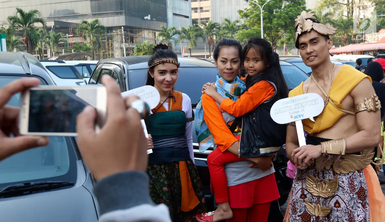 Warga berfoto bersama karakter Brama Kumbara dan Mantili saat pawai di area Car Free Day, Jakarta, Minggu (6/8). Serial yang akan tayang di SCTV ini merupakan adaptasi dari film aksi laga kolosal dengan judul yang sama. (Liputan6.com/Fery Pradolo)