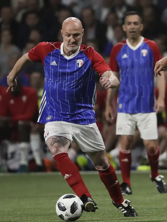 Bek Frank Leboeuf membawa saat pertandingan tim Prancis 98 dengan tim FIFA 98 di Arena U, Nanterre, Paris (12/6). Pertandingan ini memperingati 20 tahun kemenangan Prancis di Piala Dunia 1998. (AFP Photo/Thomas Samson)