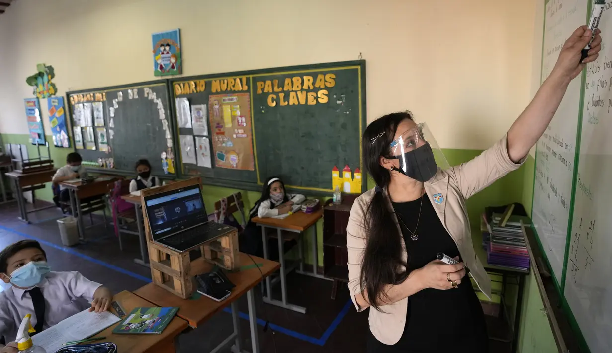 Direktur Sekolah Zulma Arnold mengajar murid kelas tiga pada hari pertama sekolah tatap muka di National School Two Celsa Speratti, Asuncion, Paraguay, Senin (30/8/2021). Sekolah tatap muka digelar setelah satu setengah tahun belajar jarak jauh di tengah pandemi COVID-19. (AP Photo/Jorge Saenz)