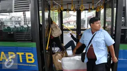 Kondektur bus Angkutan Perbatasan Terintegrasi Busway (APTB) saat menaikan penumpang di halte Transjakarta BNN, Cawang, Jakarta, Selasa (8/3/2016). Pemprov DKI kembali perbolehkan APTB kembali beroperasi dengan sejumlah syarat. (Liputan6.com/Yoppy Renato)