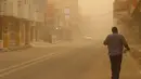 Seorang pria berjalan di jalan selama badai debu di kota Nasiriyah Irak di provinsi Dhi Qar selatan (9/4/2022). Badai debu telah melanda sebagian besar Irak, meninggalkan puluhan orang di rumah sakit dengan masalah pernapasan. (AFP/Shwan Nawzad)